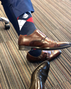 people in suits and dress shoes showing off navy red and white argyle style Transparensa Fuels socks